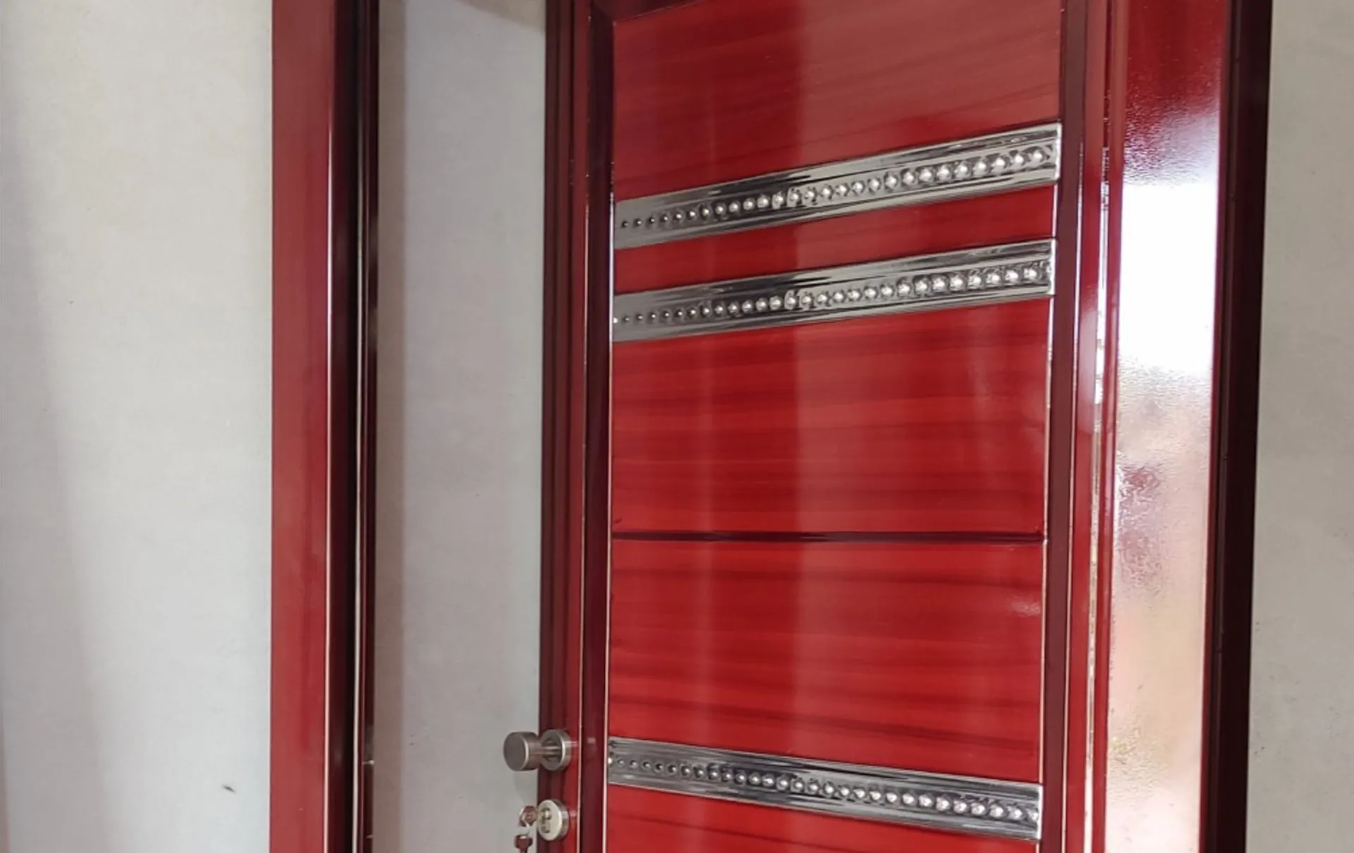 Puerta de metal en tono rojo con franjas de acero inoxidable